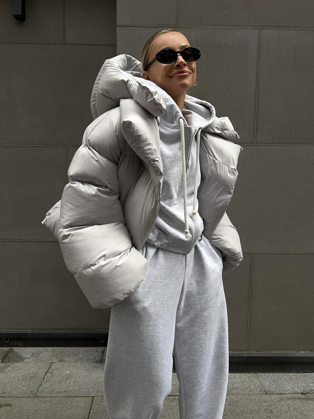 Cropped Hooded Puffer Jacket with Drawstring Hem in Light Gray — on model, hands in pockets