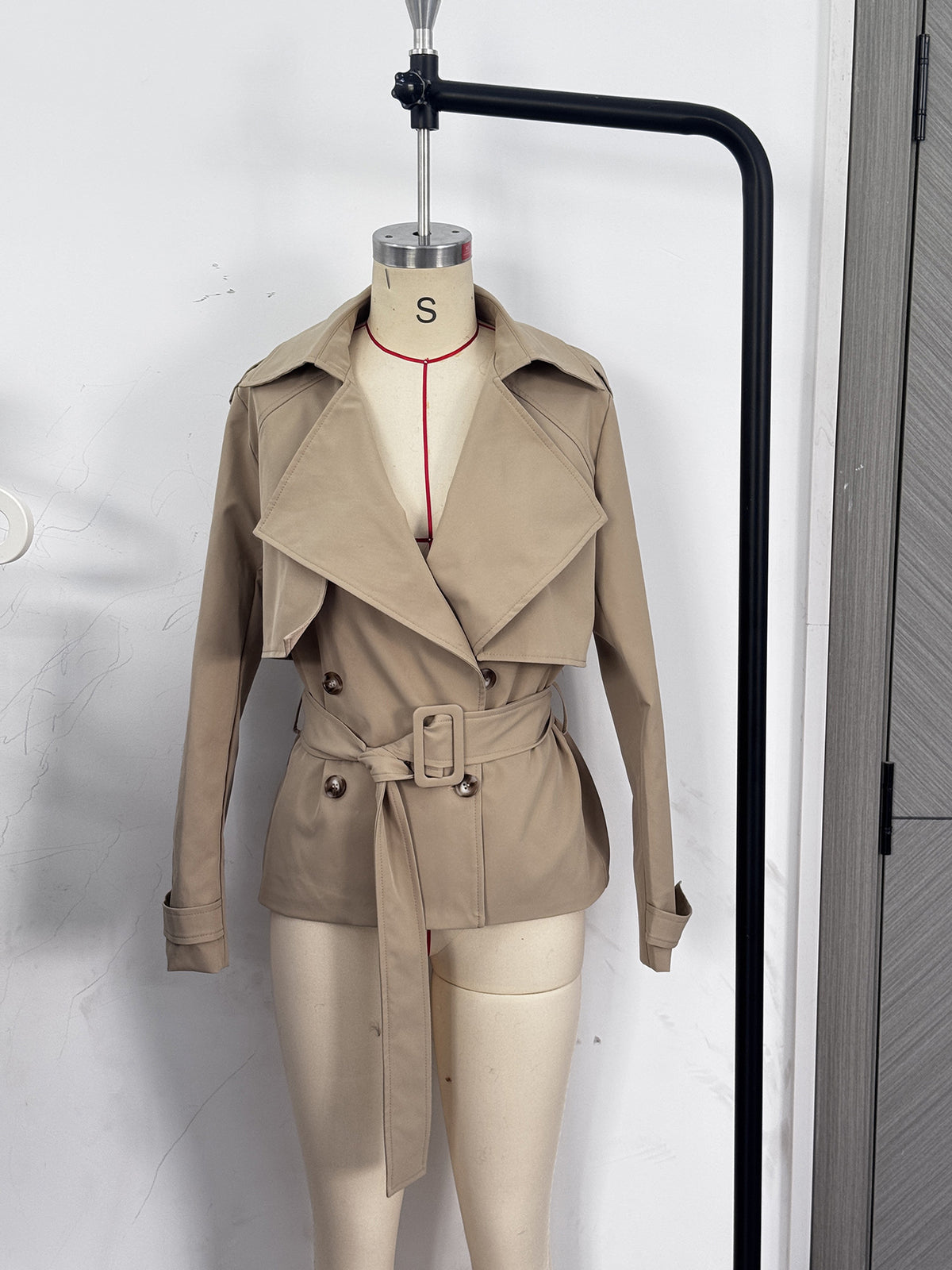 Cropped Double-Breasted Trench Jacket with Belt and Epaulettes in Khaki — front view on a dress form
