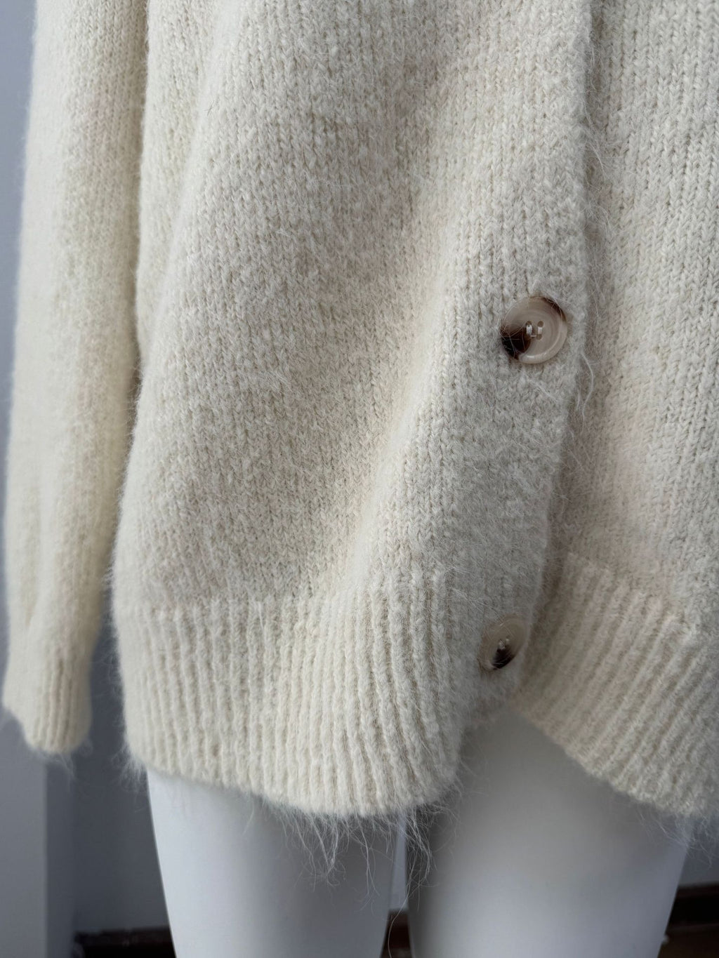 Fuzzy Wool-Blend V-Neck Button Cardigan in Ivory — close-up of the fuzzy knit and ribbed hem