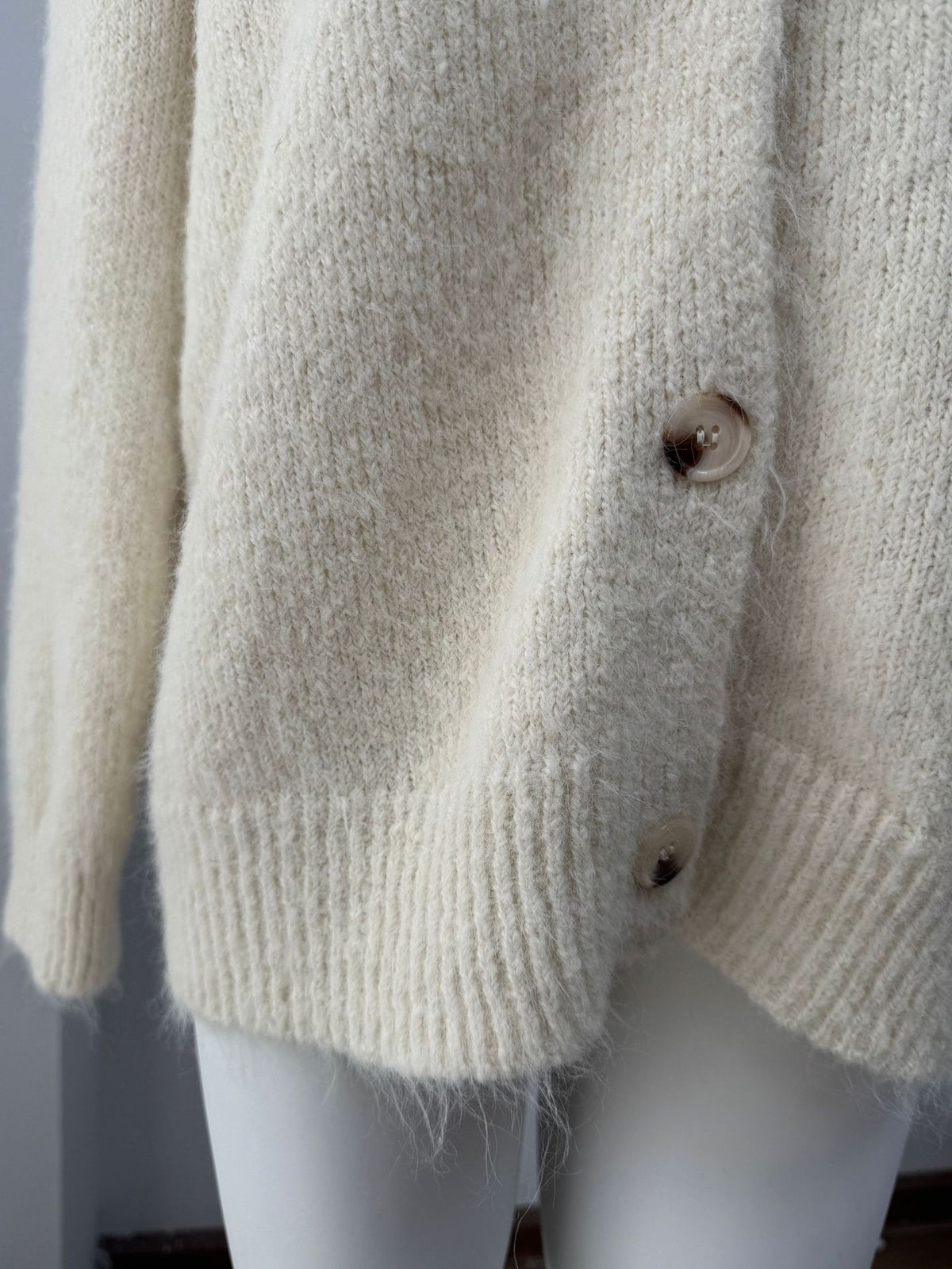 Fuzzy Wool-Blend V-Neck Button Cardigan in Ivory — close-up of the fuzzy knit and ribbed hem