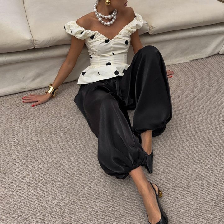 Shiny Pleated Harem Pants with Elastic Cuffs in Black — front view on model, seated