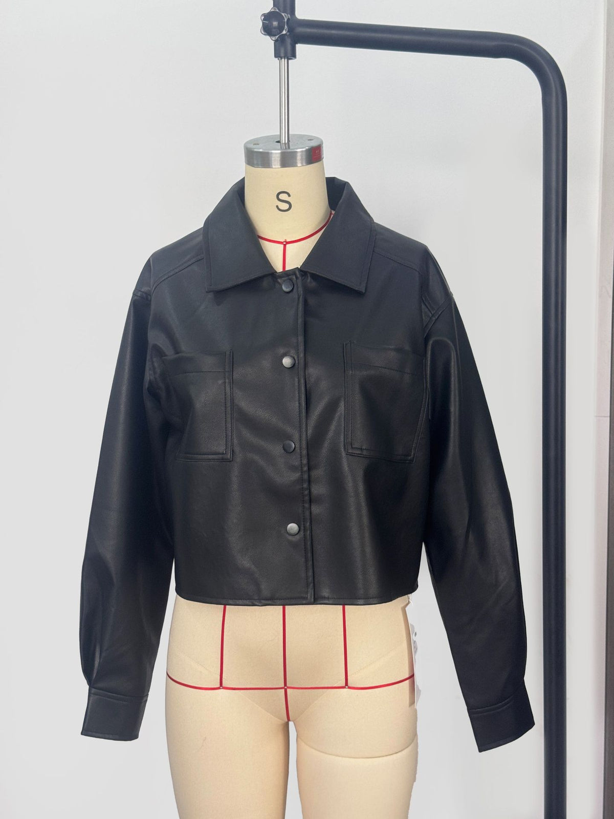 Cropped Faux Leather Shirt Jacket with Patch Pockets in Black — front view on a dress form