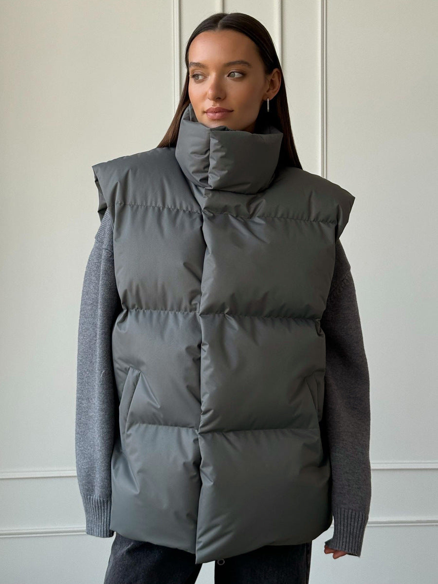 Longline Puffer Vest with High Stand Collar in Charcoal Gray — front view on model over a knit