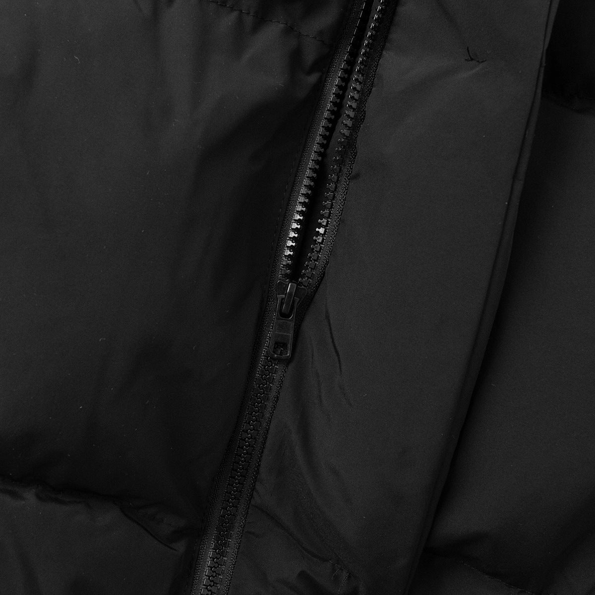 Longline Puffer Vest with High Stand Collar in Black — close-up of the front zip