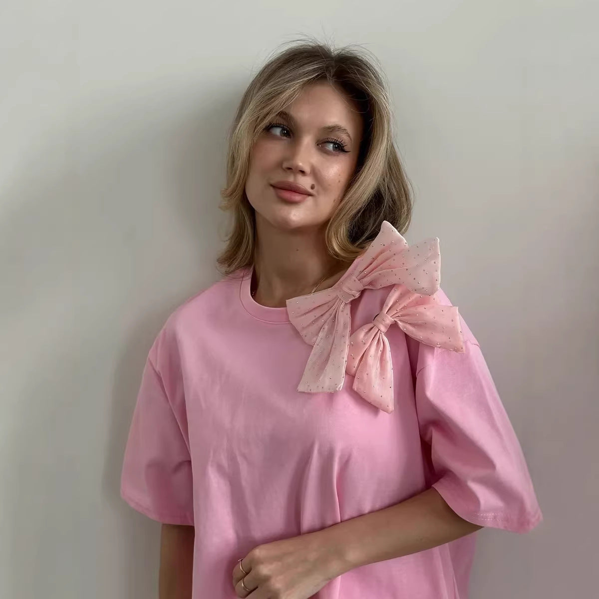 Oversized Cotton Tee with a Rhinestone Bow in Pink — bow and neckline on model