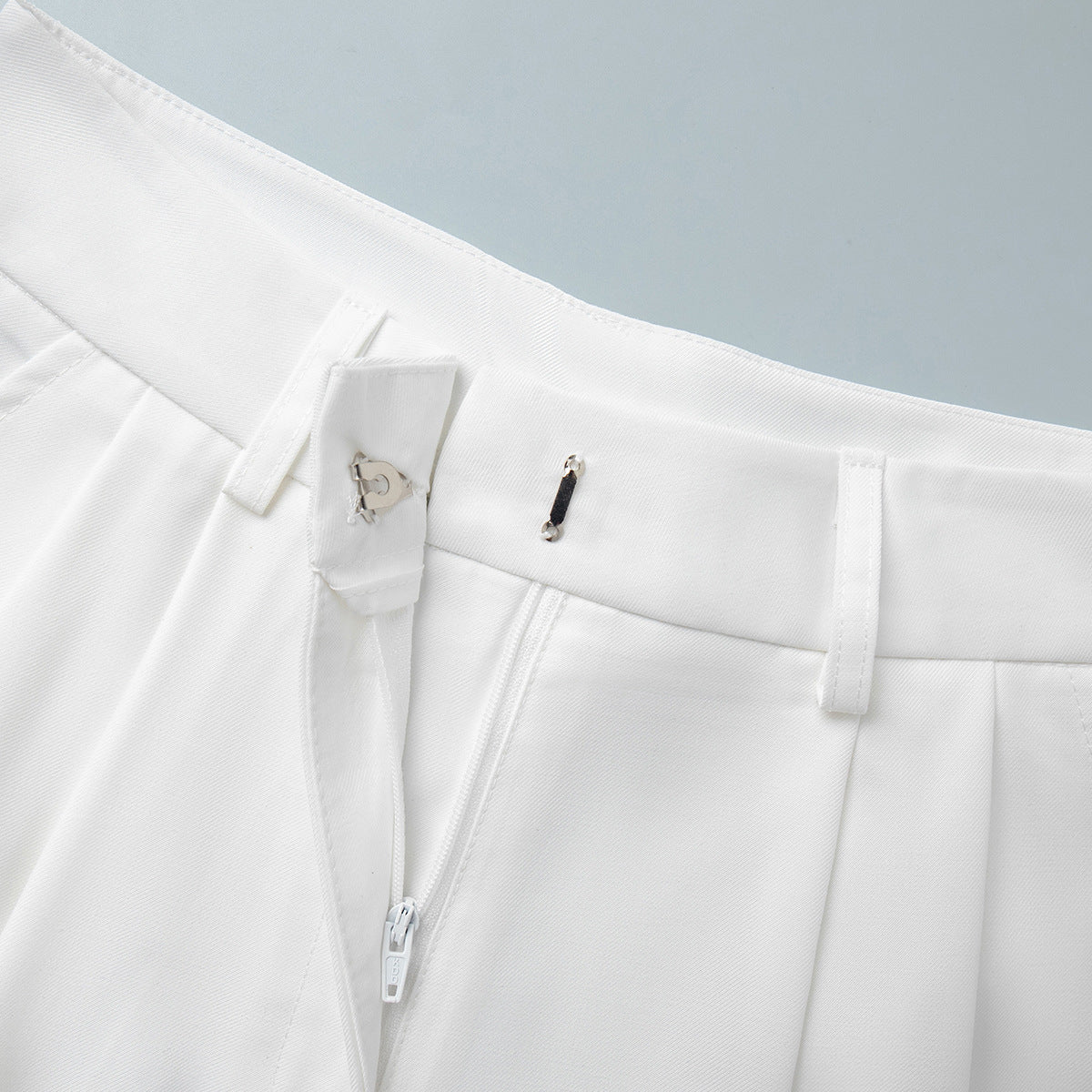 High-Waist Pleated Bermuda Shorts in White — close-up of hook-and-bar and zip