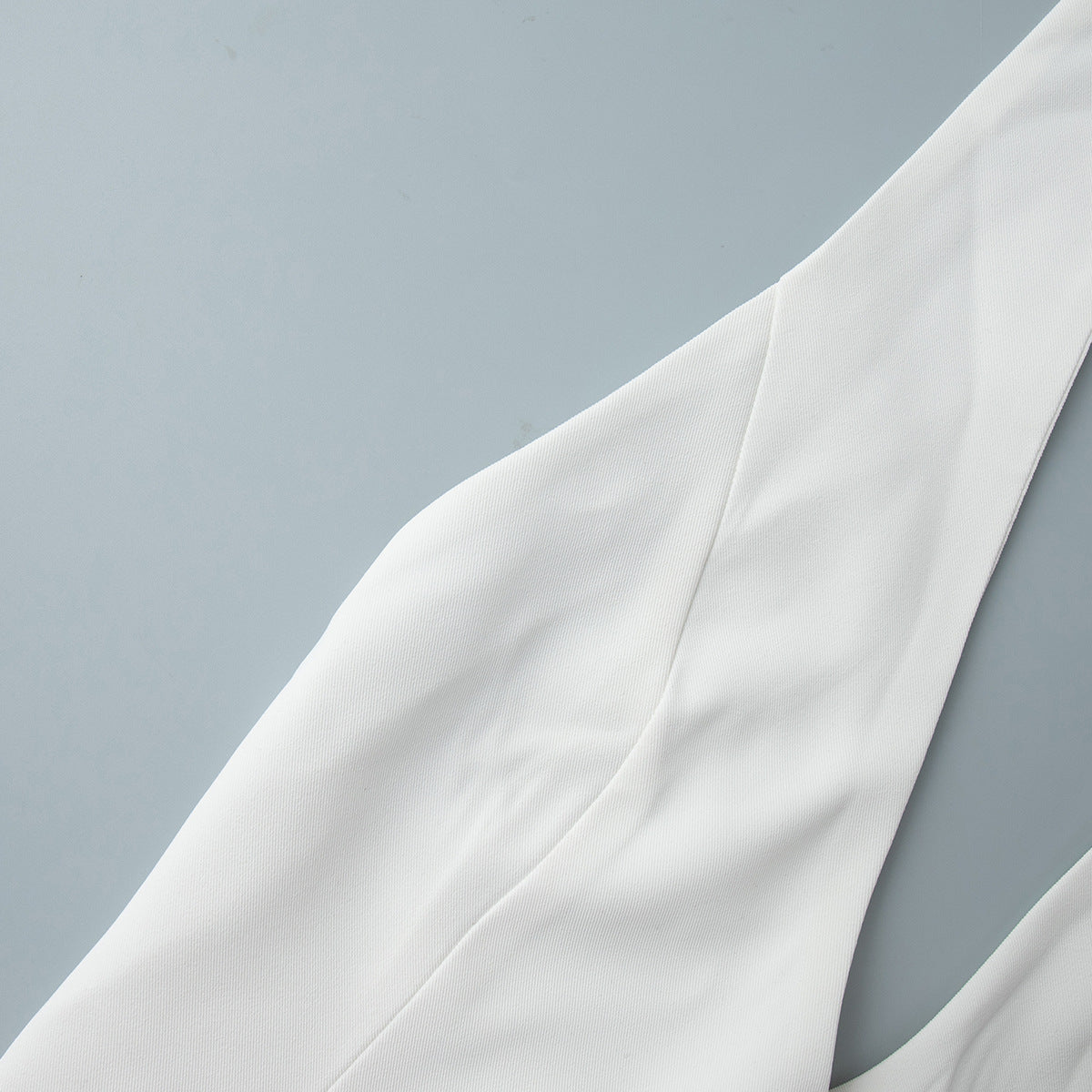 Open-Back Halter Crop Vest in White — close-up of the pointed hem and buttons