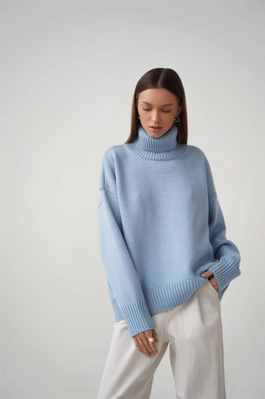 Oversized Knit Turtleneck Sweater in Powder Blue — full-length view with white trousers