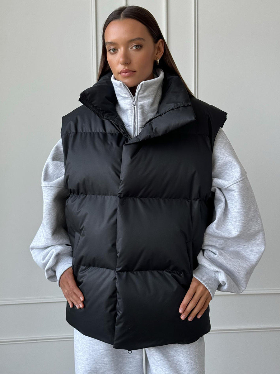 Longline Puffer Vest with High Stand Collar in Black — front view on model over a gray hoodie