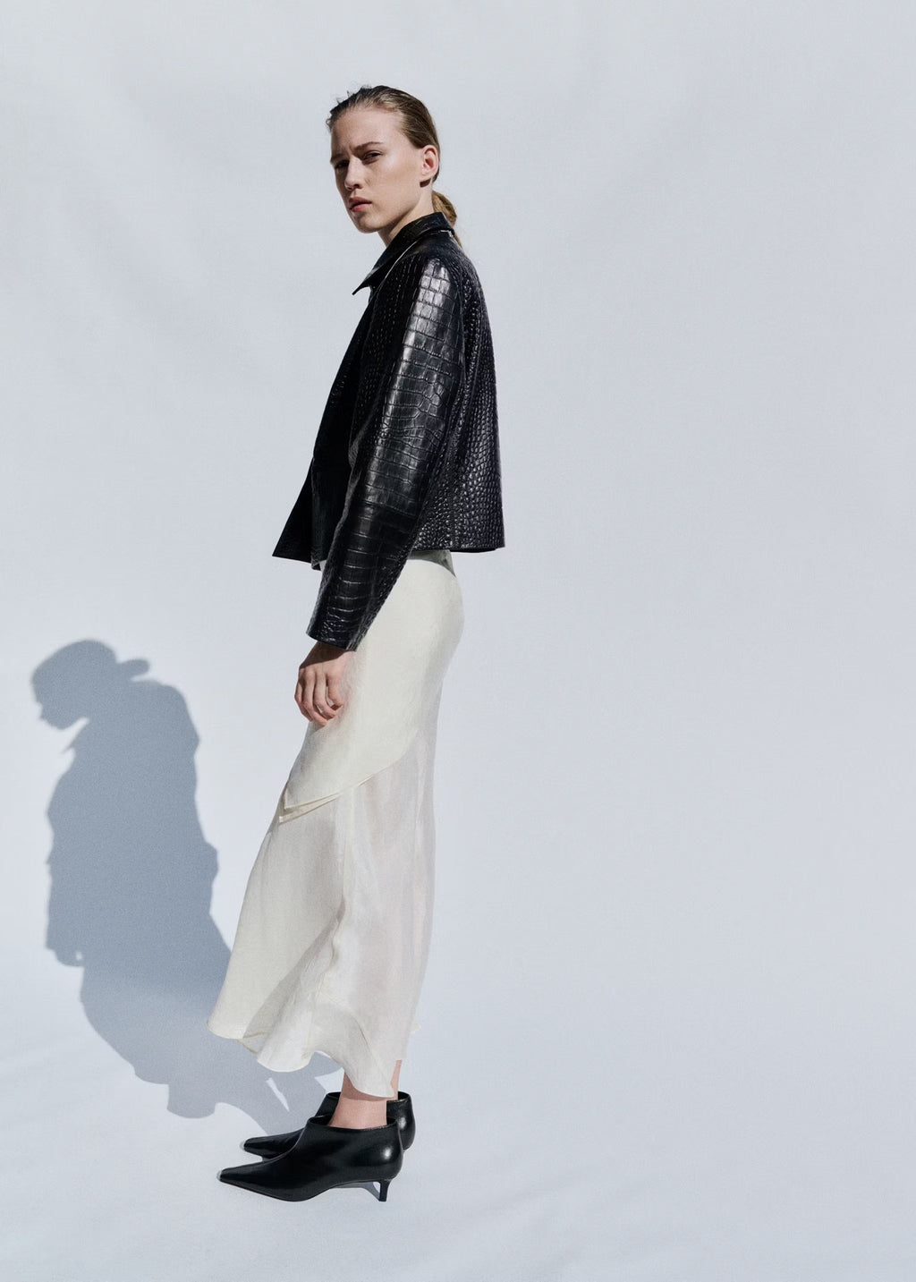 Cropped Double-Breasted Faux Leather Jacket in Black — full-length side view on model