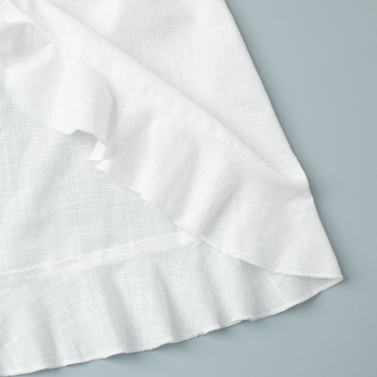 Tie-Front Cotton Mini Shirt Dress in White — close-up of the ruffled hem