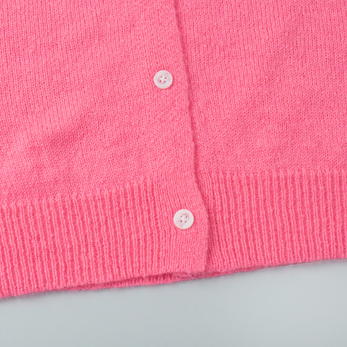 Soft Fuzzy Crew Neck Button Cardigan in Hot Pink — close-up of the ribbed hem