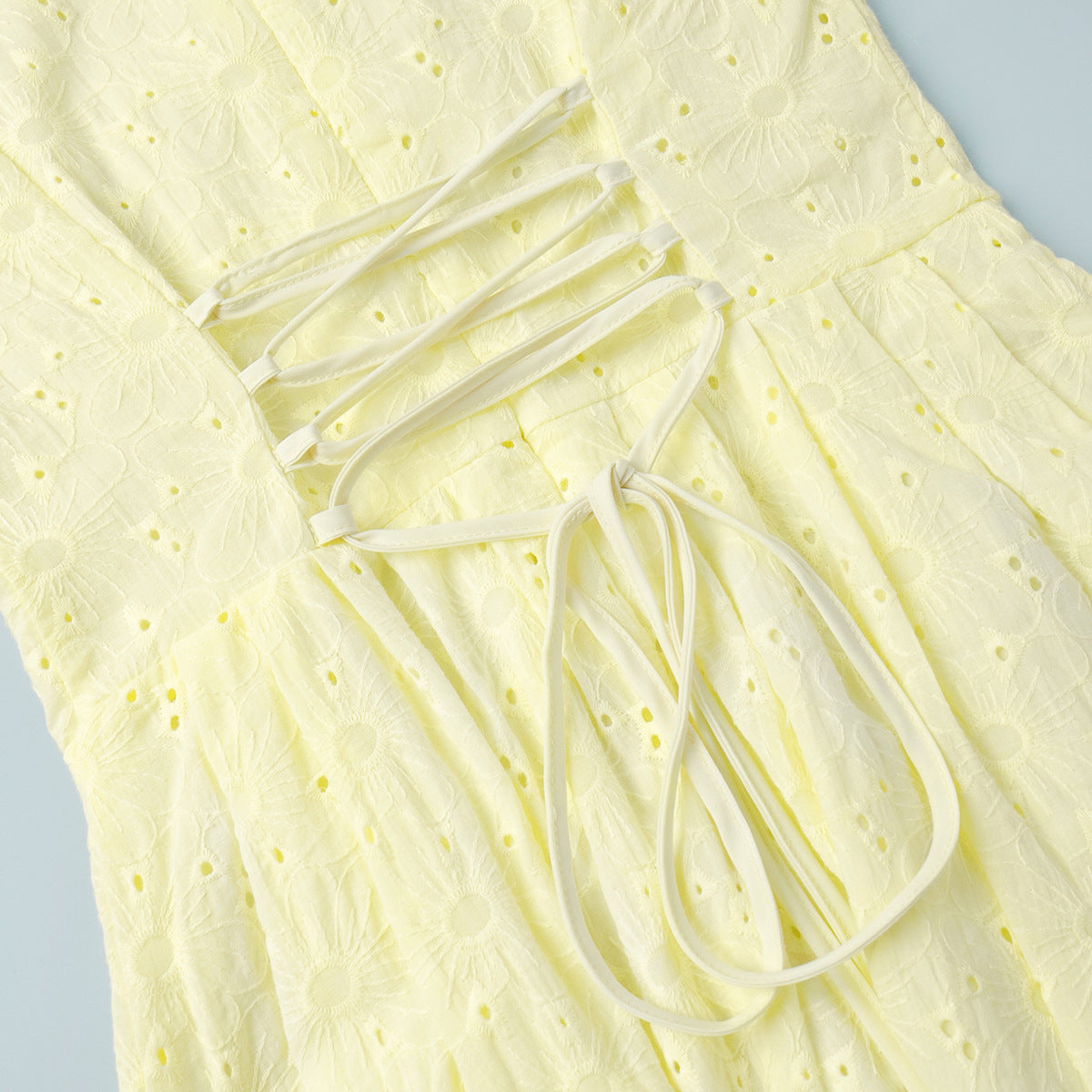Yellow Eyelet Puff-Sleeve Mini Dress in Pale Yellow — close-up of the lace-up back