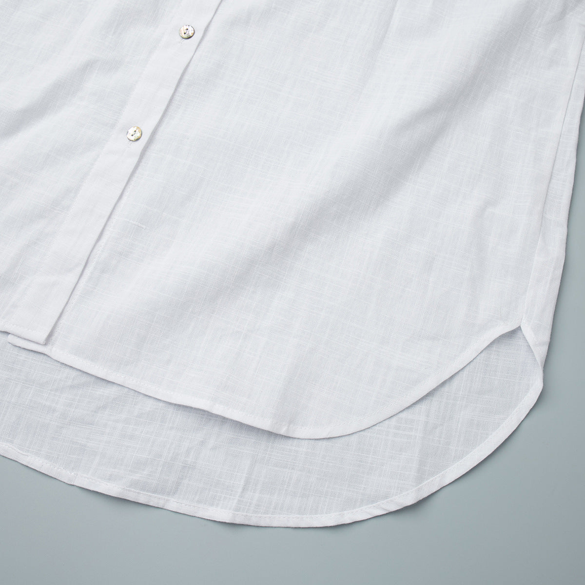 Relaxed Cotton Button-Down Shirt in White — close-up of the curved shirttail hem