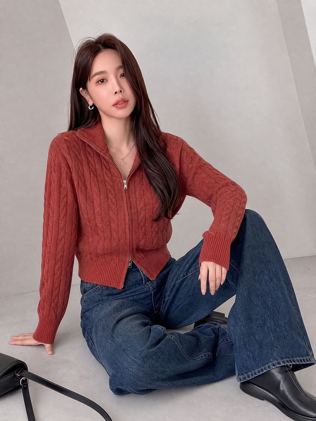 Cable-Knit Zip-Up Cardigan Sweater in Brick Red — seated view on model