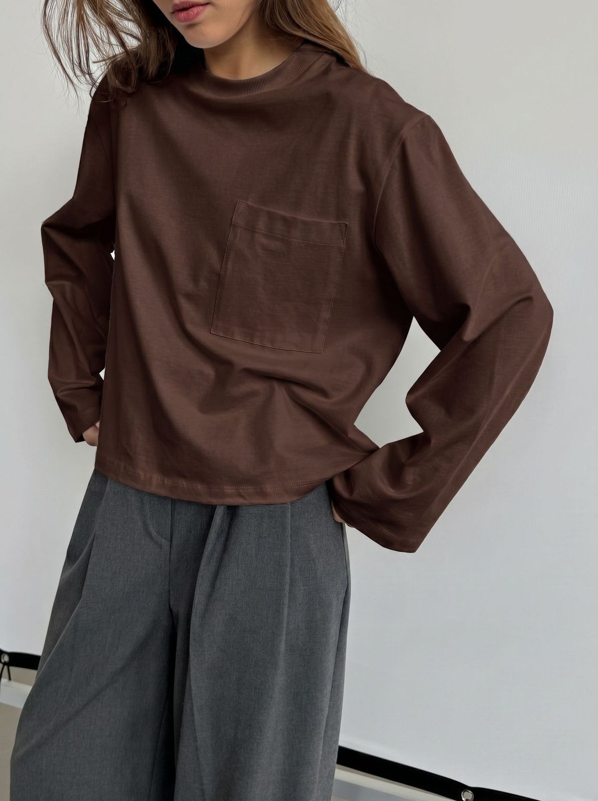 Relaxed Cotton Long-Sleeve Pocket Tee in Chocolate — front view on model with gray trousers