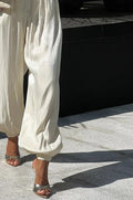 Shiny Pleated Harem Pants with Elastic Cuffs in White — on model, cropped to show pants